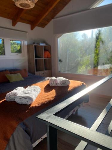 a bedroom with a bed with towels on it at Estación Ventana - cabaña al pie del cerro in San Carlos de Bariloche