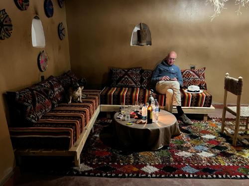 a man sitting on a couch in a living room at Dar Nomads in Mhamid