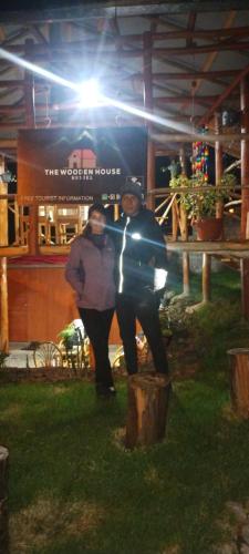 two people standing in front of a building at night at the wooden house choquequirao in Cachora
