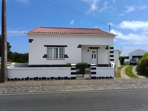 a white house with a red roof on a street at Casa da Atalaia in Angra do Heroísmo