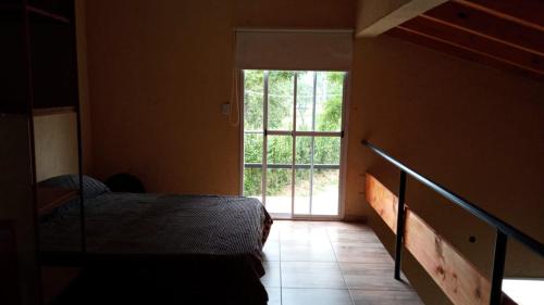 1 dormitorio con cama y ventana grande en Raíces de la Estancia en San Luis