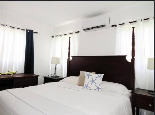 een slaapkamer met een groot wit bed met een houten hoofdeinde bij Beautiful condo in La Romana near Caleta beach in La Romana