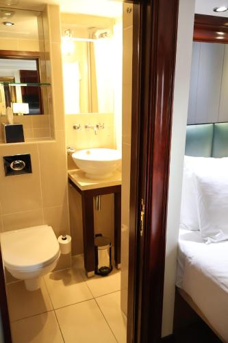a bathroom with a sink and a toilet and a bed at Dreamtel London Kensington in London