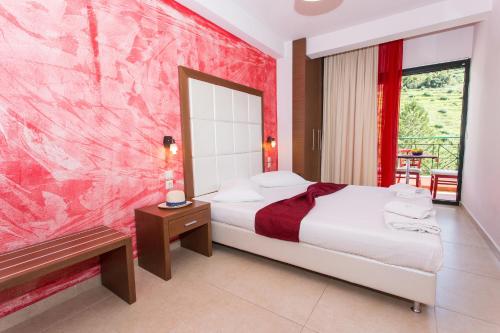 une chambre avec un lit et un mur rose dans l'établissement Irinis Garden, à Parga