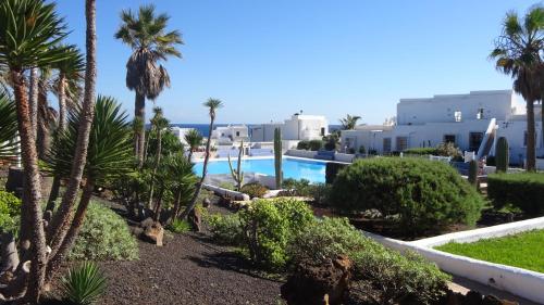een uitzicht op een resort met palmbomen en een zwembad bij Ferienwohnung mit Dachterrasse, mehreren Pools, Garten und viel Ruhe in Poris de Abona