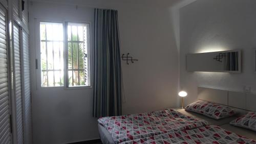 Schlafzimmer mit einem Bett und einem Fenster in der Unterkunft Ferienwohnung mit Dachterrasse, mehreren Pools, Garten und viel Ruhe in Poris de Abona