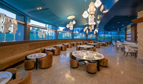 a restaurant with tables and chairs and windows at Lykia World Links Golf Antalya in Denizyaka
