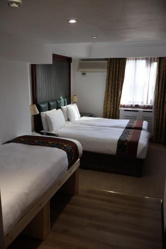 a hotel room with two beds and a window at Dreamtel London Kensington in London