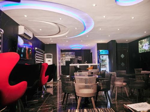 a restaurant with chairs and tables and a bar at Triple Tee Luxury Hotel & Service Apartments Surulere in Lagos