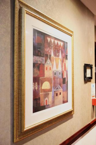 a painting in a gold frame hanging on a wall at Dreamtel London Kensington in London
