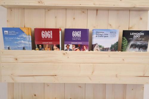 a shelf with books on top of a wooden wall at Dreamtel London Kensington in London