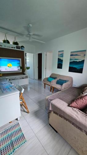 ein Wohnzimmer mit 2 Betten und einem Flachbild-TV in der Unterkunft Bertioga Praia do SESC - Apartamento de 2 quartos in Bertioga