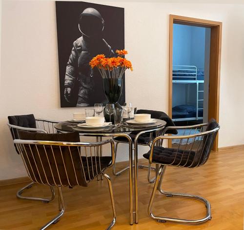 une table noire avec des chaises et un vase de fleurs dans l'établissement SPACE AGE Design-Luxus-Apartment, Terrasse, Zentral, à Gera