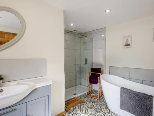 a bathroom with a tub and a sink and a mirror at 3 Bed in Wroxham 79211 in Dilham