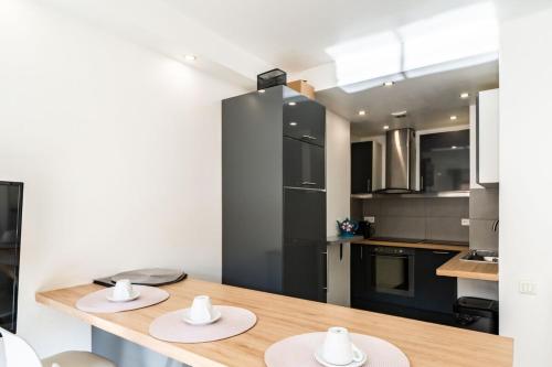 - une cuisine avec une table en bois et un réfrigérateur noir dans l'établissement Wdf one bedroom 1 min walk to Martinez hotel, à Cannes