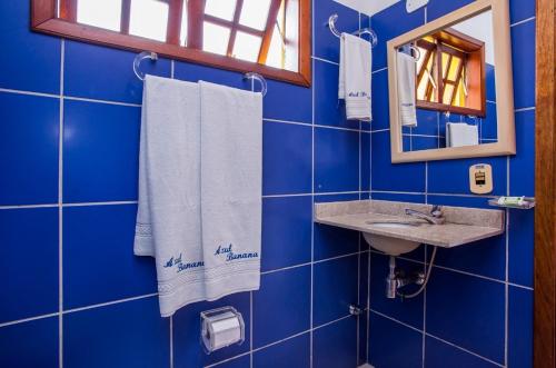 a blue tiled bathroom with a sink and a mirror at Pousada Azul Banana - Maresias in Maresias