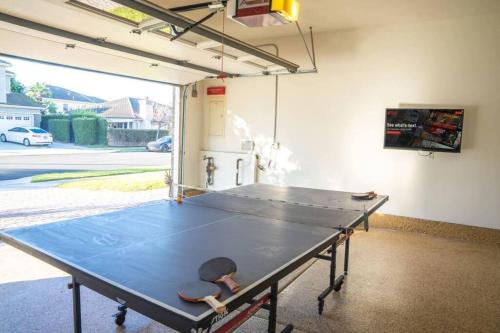 a ping pong table in a garage with a ping pong ball at Ping Pong, A/C, Netflix, Grill, Jacuzzi Tub, W/D in Placentia