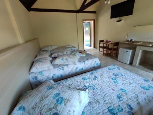 two beds sitting in a room with a kitchen at Pousada temática Estrada Real in Caxambu
