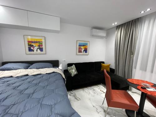 ein Schlafzimmer mit einem Bett, einem Sofa und einem Tisch in der Unterkunft Midnight Apartments in Tirana
