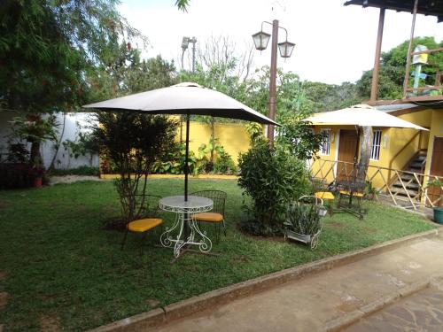 a table and chairs under an umbrella in a yard at Hostal Juarez Ataco in Concepción de Ataco