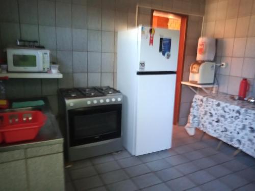 a kitchen with a stove and a white refrigerator at Casa de Porto de Galinhas 137 in Porto De Galinhas