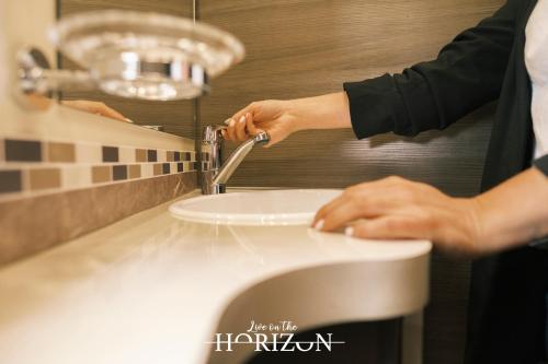 a person is washing a sink in a bathroom at Live On The Horizon 1 in Ribadesella