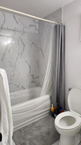 y baño con bañera, aseo y ducha. en Modern 2 Bedroom Basement Suite at West Edmonton en Edmonton