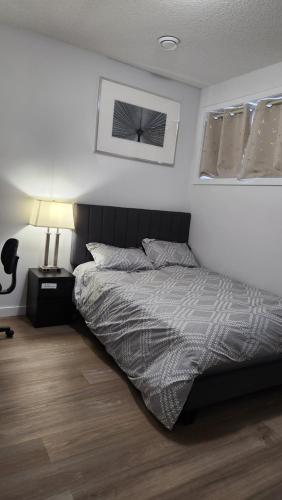 Un dormitorio con una cama y una lámpara. en Modern 2 Bedroom Basement Suite at West Edmonton en Edmonton