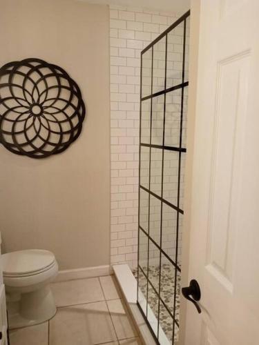 a bathroom with a toilet and a glass shower door at House Close to Downtown, Airport, Raymond James Stadium, and Many More Places in Tampa