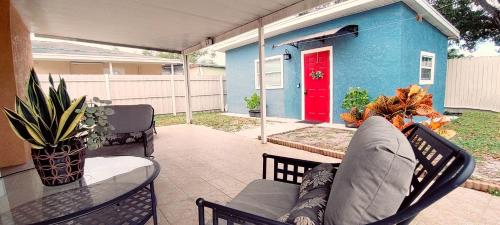 a patio with a table and chairs and a red door at House Close to Downtown, Airport, Raymond James Stadium, and Many More Places in Tampa