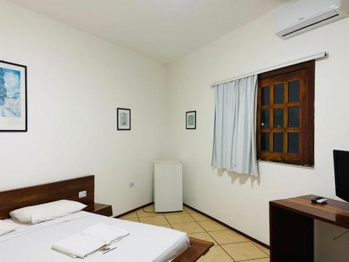 a bedroom with a bed and a desk and a window at Hotel Pousada Canoa Quebrada in Canoa Quebrada