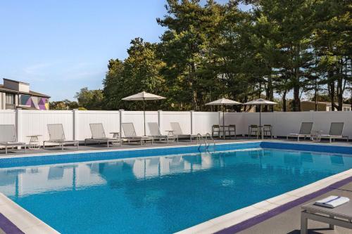 a swimming pool with chairs and umbrellas at Spark By Hilton Mystic Groton in Mystic