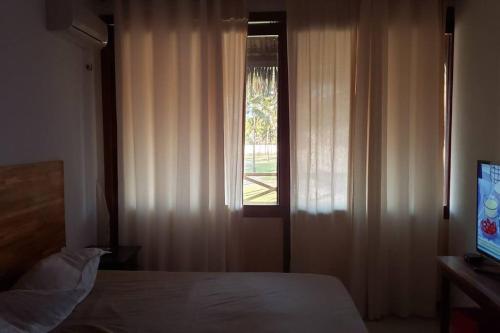1 dormitorio con 1 cama y una ventana con cortinas en Flecheiras Eco Residence Un302, en Flecheiras
