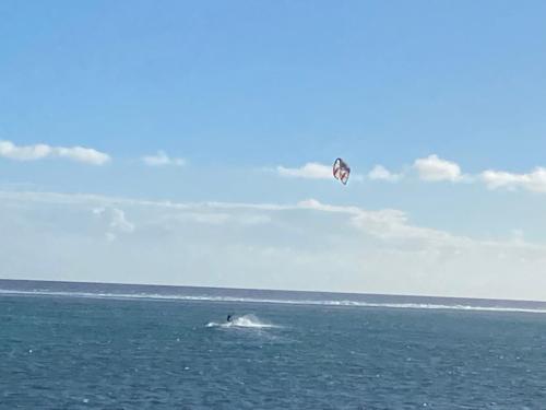 a person flying a kite over the ocean at coral coast FIJI in Sigatoka