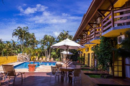 a patio with a table and chairs and a pool at Pousada Azul Banana - Maresias in Maresias