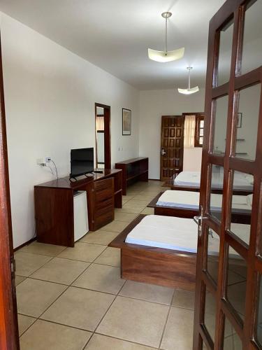 a room with three beds and a television in it at Hotel Pousada Canoa Quebrada in Canoa Quebrada