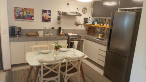 a kitchen with a small table and a refrigerator at Nannai Residence, Beira-mar - Porto de Galinhas / Muro Alto (BDJ06) in Porto De Galinhas