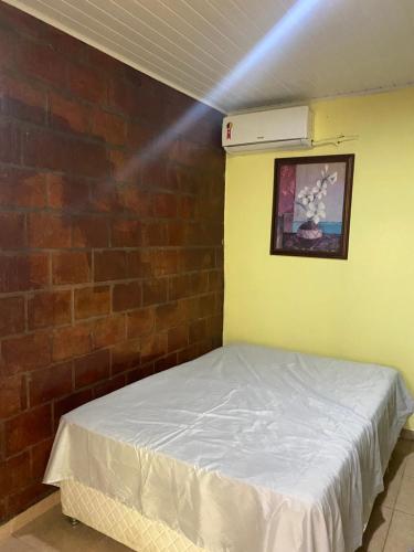 Bett in einem Zimmer mit Ziegelwand in der Unterkunft Casa Residencial Tarumã in Manaus