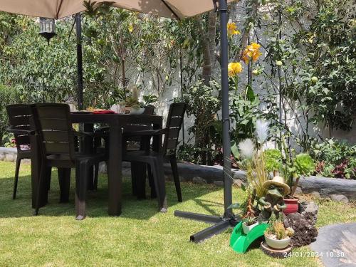 a table and chairs under an umbrella in a garden at Casa Baraquel in Arequipa