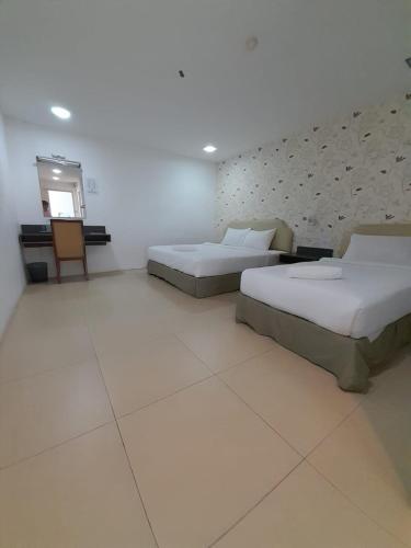 a bedroom with two beds and a television in it at Hotel Twelve at 12 Kuantan Centre in Kuantan