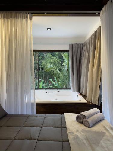 a bedroom with a large window and a bath tub at Sítio Balango: Seu refúgio em Domingos Martins. Chalés para casais e casa para grupo de pessoas in Domingos Martins