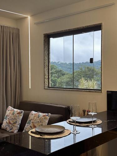 a living room with a table and a large window at Sítio Balango: Seu refúgio em Domingos Martins. Chalés para casais e casa para grupo de pessoas in Domingos Martins