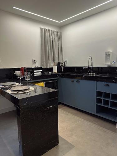 a large kitchen with black counters and a sink at Sítio Balango: Seu refúgio em Domingos Martins. Chalés para casais e casa para grupo de pessoas in Domingos Martins
