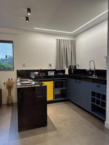 a large kitchen with black counters and yellow appliances at Sítio Balango: Seu refúgio em Domingos Martins. Chalés para casais e casa para grupo de pessoas in Domingos Martins