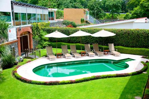 a swimming pool with chairs and umbrellas in a yard at Nuevo Amanecer in Tepoztlán