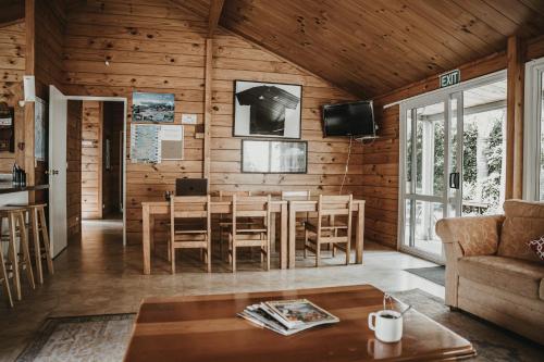 una sala de estar con mesa y sillas en una cabaña en Tatahi Cove Back Packer en Hahei