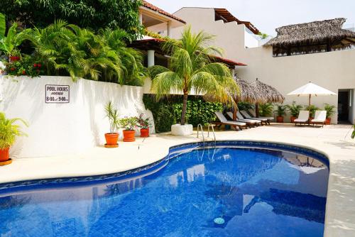 a pool in front of a house with palm trees at Villas San Sebastian in Zihuatanejo