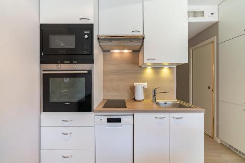 La cuisine est équipée de placards blancs, d'un four micro-ondes et d'un évier. dans l'établissement Brand new one bedroom 2min walk to Carlton hotel, à Cannes