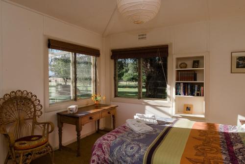 a bedroom with a bed and a desk and two windows at Corowa Oakleigh Hideaway in Hopefield