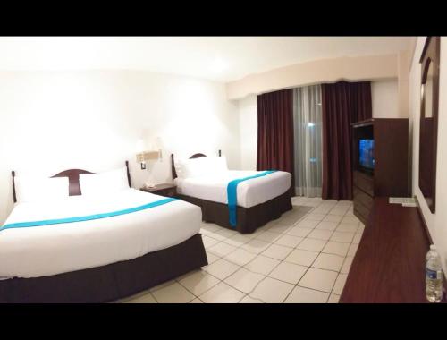 um quarto de hotel com duas camas e uma televisão de ecrã plano em HOTEL REAL FLOR DE MARIA em Comitán de Domínguez